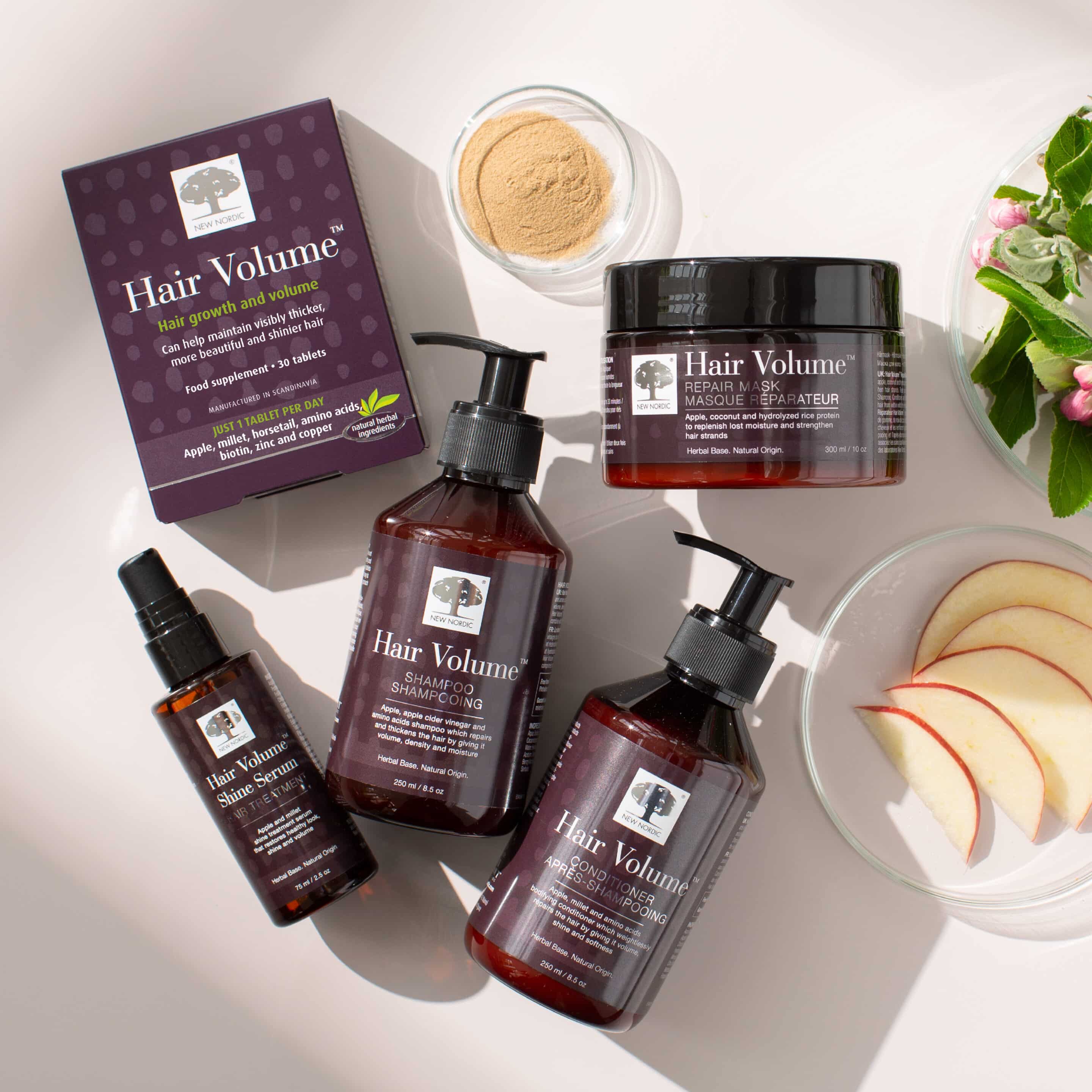 Hair Volume™ hair treatment range products laid out on a flat surface with some additional items on it